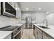Stylish kitchen with stainless steel appliances, white subway tile, gray cabinets and wood tile floors at 3764 Laughing Dove Ave, Sun City Center, FL 33573