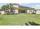 View of home and backyard with lush green lawn, patio doors, landscaping and fenced perimeter at 3952 Bonfire Dr, Odessa, FL 33556