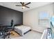 Modern bedroom featuring dark accent wall, a ceiling fan, and natural light from the window at 3952 Bonfire Dr, Odessa, FL 33556
