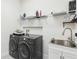 Laundry room featuring a modern washer and dryer set, utility sink, and wire shelving at 3952 Bonfire Dr, Odessa, FL 33556