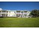 Back of townhomes featuring private patios, outdoor stairs, and lush green lawn for outdoor enjoyment at 4816 Snook Se Dr # F, St Petersburg, FL 33705