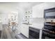 Kitchen view showing stainless steel sink, white cabinets and black appliances with sight lines to living room at 4816 Snook Se Dr # F, St Petersburg, FL 33705