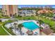 Aerial view of a hexagon-shaped community pool with lounge chairs, tiki umbrellas, landscaping, and building views at 4900 Brittany S Dr # 211, St Petersburg, FL 33715
