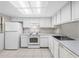 Bright kitchen with all white cabinets, appliances and tile flooring under a large skylight at 4991 Puritan Cir # 522, Tampa, FL 33617
