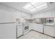 Bright kitchen features white appliances, white cabinets, and tile flooring beneath a large skylight at 4991 Puritan Cir # 522, Tampa, FL 33617