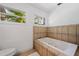 Bathroom featuring a large soaking tub tiled with a decorative border, a toilet, and a window at 5660 Hobson Ne St, St Petersburg, FL 33703