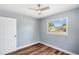 Comfortable bedroom with wood flooring, a ceiling fan, and a window offering a view of the neighborhood at 5660 Hobson Ne St, St Petersburg, FL 33703