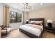 This stylish primary bedroom features a comfortable bed, elegant chandelier, and a large picture window at 5703 Silverside Pine Ct, Lakewood Ranch, FL 34211