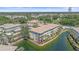 Aerial view of condo building surrounded by pond with lush landscaping and screened in lanai at 600 Gardens Edge Dr # 614, Venice, FL 34285
