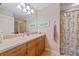 This bathroom has wood cabinets, neutral walls, and a shower with a bamboo patterned curtain at 600 Gardens Edge Dr # 614, Venice, FL 34285