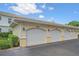 Row of garages featuring white doors, decorative lighting, and well-kept landscaping around the parking area at 600 Gardens Edge Dr # 614, Venice, FL 34285