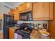 Kitchen featuring black appliances, wood cabinetry, and granite countertops offer functionality and style at 600 Gardens Edge Dr # 614, Venice, FL 34285