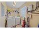 Well-equipped laundry room with modern washer and dryer, storage shelves, and a tankless hot water heater at 600 Gardens Edge Dr # 614, Venice, FL 34285