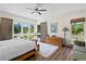 Bright bedroom with large windows showcasing a lush garden view, wood floors, and modern ceiling fan at 7508 N Ola Ave, Tampa, FL 33604