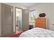 Bedroom with wood floors, a window with greenery, and an open door to the bathroom at 7508 N Ola Ave, Tampa, FL 33604