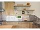 Bright kitchen featuring stainless steel backsplash, wood cabinets, open shelving, and granite countertops at 7508 N Ola Ave, Tampa, FL 33604