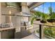 Outdoor kitchen on a deck with a built-in grill, counter space, and hanging plants at 7508 N Ola Ave, Tampa, FL 33604