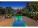 Backyard pool lit up at night featuring outdoor seating and mature, lush tropical landscaping at 7508 N Ola Ave, Tampa, FL 33604