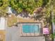 Aerial view of a pool and patio with a pink umbrella, screened-in pool area, and lush tree coverage at 7660 Holiday Dr, Spring Hill, FL 34606