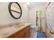 Bathroom featuring a wooden vanity with decorative mirror, tiled floor and shower, and ample lighting at 7660 Holiday Dr, Spring Hill, FL 34606