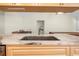 Close-up showcasing a stainless steel kitchen sink embedded in a marble countertop, complemented by light wood cabinets at 7660 Holiday Dr, Spring Hill, FL 34606