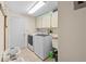 Laundry room with washer, dryer, overhead cabinets, and tiled flooring at 7660 Holiday Dr, Spring Hill, FL 34606