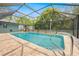 The screened-in pool area showcases clear blue water, brick pavers, and a sturdy pool ladder at 7660 Holiday Dr, Spring Hill, FL 34606