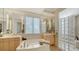 Lavish bathroom featuring a soaking tub, bright mirrors, modern fixtures, and a glass block shower at 770 N Manasota Key Rd, Englewood, FL 34223