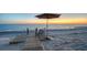 Relaxing beach scene with chairs and umbrella on a wooden walkway overlooking the ocean at sunset at 770 N Manasota Key Rd, Englewood, FL 34223