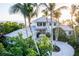Beautiful two-story home with a circular driveway, lush landscaping, and a glimpse of the ocean at 770 N Manasota Key Rd, Englewood, FL 34223