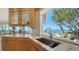 Kitchen with stainless steel sink near the window, custom cabinetry, and stunning views of the ocean and outdoor seating at 770 N Manasota Key Rd, Englewood, FL 34223