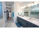 Bright bathroom boasts double vanity with sleek gray cabinets, marble floors, and glass shower at 9263 Barrier Coast Trl, Parrish, FL 34219