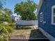 Home's backyard featuring a white fence, a fire pit, and surrounding tropical plants at 10562 Lake Dr, Seminole, FL 33772