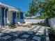 Cozy backyard with stone patio, outdoor seating, decorative plants, and a well-maintained lawn at 10562 Lake Dr, Seminole, FL 33772