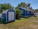 View of the home's exterior, featuring blue siding, a shed, and landscaping at 10562 Lake Dr, Seminole, FL 33772