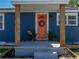 Close-up of a coral front door with a wreath, flanked by wooden pillars and plants at 10562 Lake Dr, Seminole, FL 33772