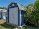 Backyard shed with secure doors, stone base, and surrounding tropical plants at 10562 Lake Dr, Seminole, FL 33772