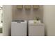 Efficient laundry room features modern washer and dryer, overhead storage baskets, and a clean, organized layout at 10824 Keato Beach Ct, Tampa, FL 33647