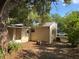 View of the backyard featuring the home's exterior with tan siding and metal roof, surrounded by mature trees and foliage at 1106 Woodlawn Ave, Plant City, FL 33563