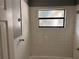 Bathroom with white tiled walls, window, shower, and grey painted accents at 1106 Woodlawn Ave, Plant City, FL 33563