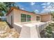 Beige one-story home featuring the back exterior with a set of windows and a partial patio area at 11210 Wheeling Dr, Tampa, FL 33625