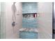 Modern shower with blue accent tile, a built-in seat, a shower head and a convenient niche for toiletries at 11210 Wheeling Dr, Tampa, FL 33625