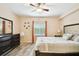 Bright bedroom featuring a ceiling fan, wood-look floors, and a large window dressed with orange curtains at 1231 Godavari Way # 103, Wesley Chapel, FL 33543