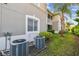 Exterior view of the condo featuring a window, screened balcony and landscaped grounds with A/C unit at 1231 Godavari Way # 103, Wesley Chapel, FL 33543