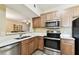 Well-lit kitchen featuring stainless steel appliances and a breakfast bar overlooking the living area at 1231 Godavari Way # 103, Wesley Chapel, FL 33543