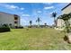 Expansive backyard with lush lawn, palm trees, and serene water views at 126 1St E St # 102, Tierra Verde, FL 33715