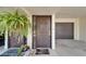 Inviting front door with hanging fern, decorative plant, welcome mat and garage access at 126 1St E St # 102, Tierra Verde, FL 33715