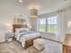 Bright bedroom with scenic view from the large windows, accompanied by a wooden bed frame and soft ottoman at 17130 Moonflower Dr, Venice, FL 34293
