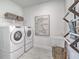 Efficient laundry room equipped with a washer and dryer, sink, and shelving for organized storage at 17130 Moonflower Dr, Venice, FL 34293