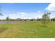Spacious backyard with lush green grass extending to a picturesque pond surrounded by neighborhood homes at 17200 Luminous Ave, Venice, FL 34293